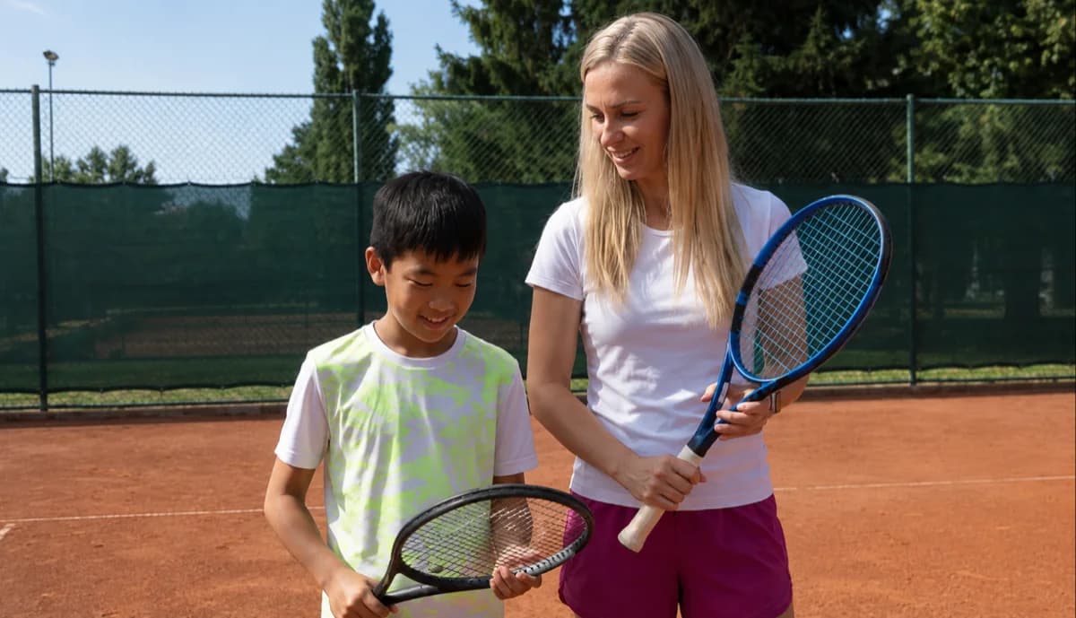 Tennis coach with a young player on a clay court